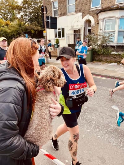 Photo of a runner petting her dog while running the London Marathon